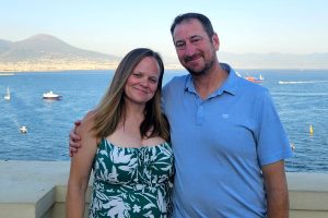 A man and woman stand in front of water.
