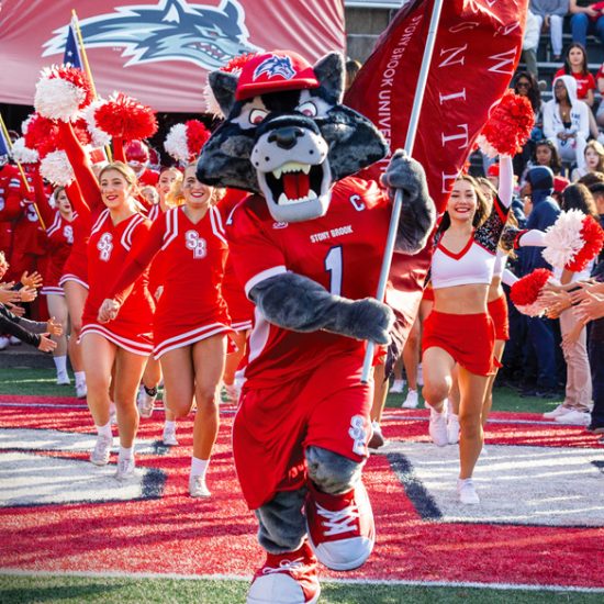 Wolfie running in front of cheerleaders